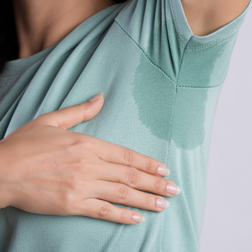 Beauty Science Excessive Sweating Woman with an underarm sweat patch on a green top, for excessive sweating and hyperhidrosis treatment