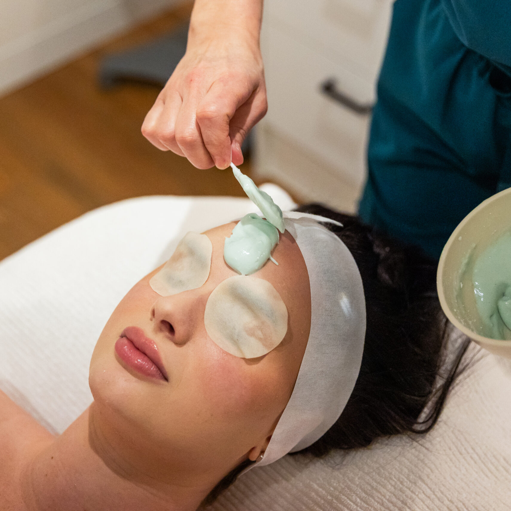 Beauty Science Spa treatment with green clay mask applied to client's face, focusing on skin and wellness fusion.